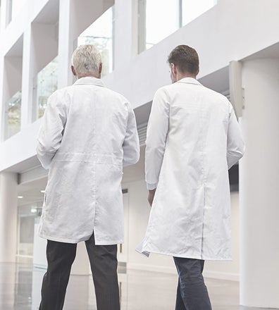 Old doctor and young doctor walking