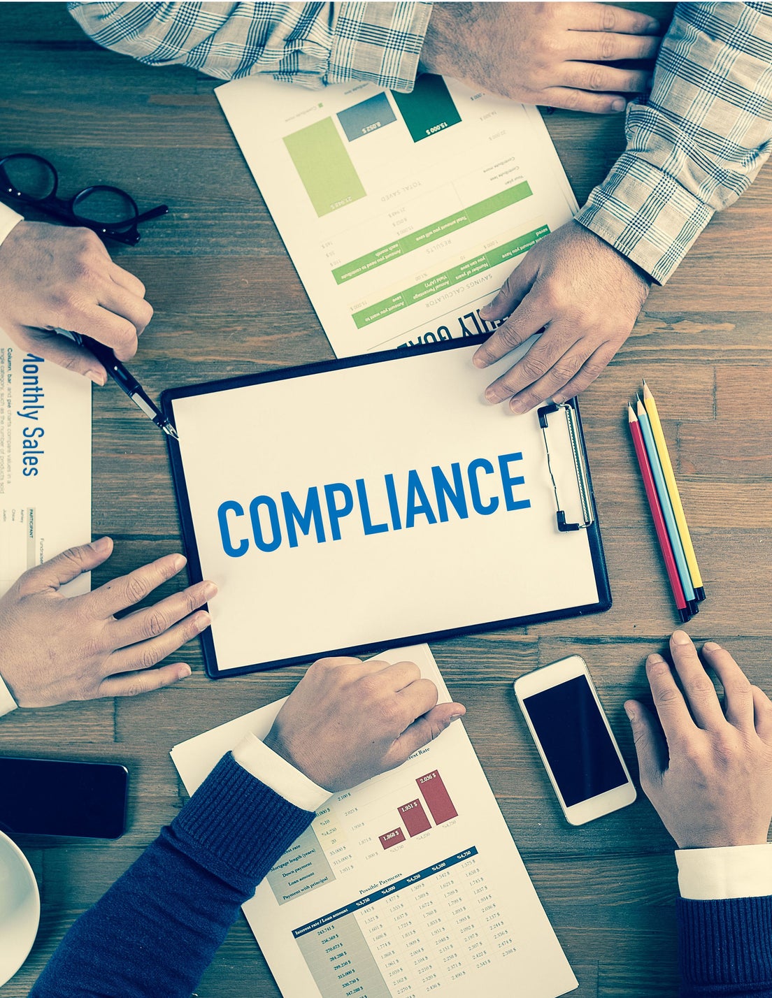 people sitting around a table working on compliance